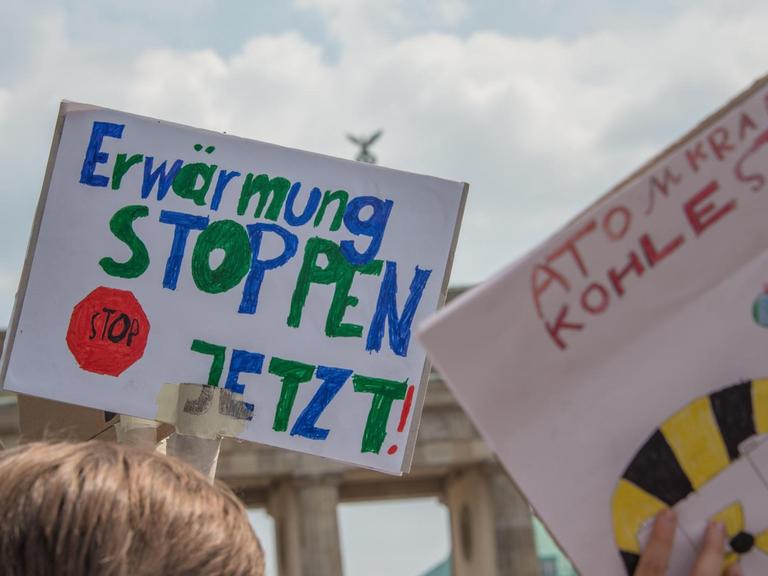 Demonstration der "Friday for Future"-Bewegung in Berlin: Im Hintergrund ist das Brandenburger Tor zu sehen, im Vordergrund wird ein Schild mit der Aufschrift "Erwärmung stoppen jetzt" hochgehalten.