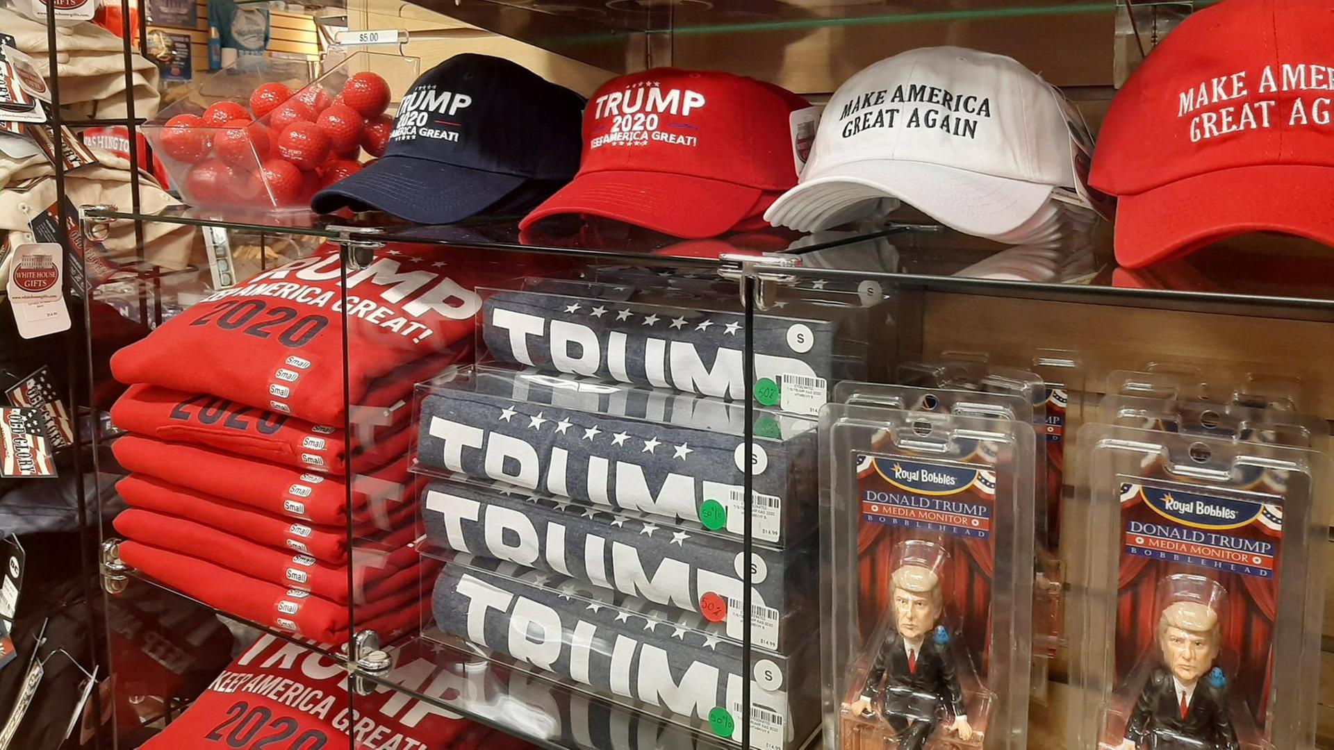 Trump-Mützen, Trump-Tassen, Trump-Pullover und Trump-Figuren warten in einem Regal auf Abnehmer. Trump-Mützen, Trump-Tassen, Trump-Pullover und Trump-Figuren warten in einem Regal auf Abnehmer.