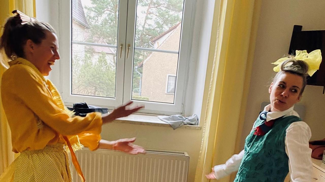 Zwei junge Frauen in bunten Kostümen stehen sich gegenüber und gestikulieren mit den Armen. Zwei junge Frauen in bunten Kostümen stehen sich gegenüber und gestikulieren mit den Armen.