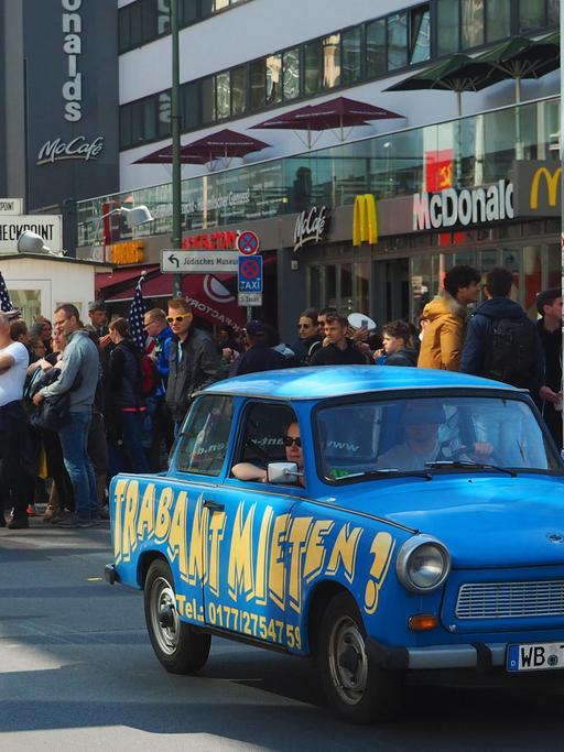 Trabis - Mietautos der "Trabi Safari" -, mit Touristen an Bord fahren am 15.05.2016 in Berlin am ehemaligen innerdeutschen Grenzübergang Checkpoint Charlie vorbei.