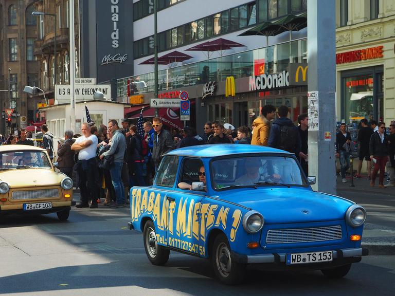 Trabis - Mietautos der "Trabi Safari" -, mit Touristen an Bord fahren am 15.05.2016 in Berlin am ehemaligen innerdeutschen Grenzübergang Checkpoint Charlie vorbei.