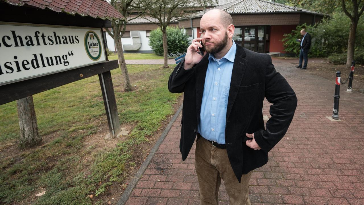 Der NPD-Politiker Stefan Jagsch steht vor dem Gemeinschaftshaus von Altenstadt-Waldsiedlung und telefoniert. 