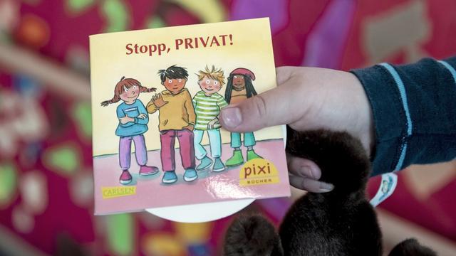 Ein Kind hält in einer Kita in Berlin bei dessen Vorstellung das neue Pixi-Buch mit dem Titel "Stopp, PRIVAT!"