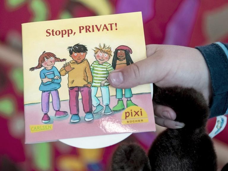 Ein Kind hält in einer Kita in Berlin bei dessen Vorstellung das neue Pixi-Buch mit dem Titel "Stopp, PRIVAT!"
