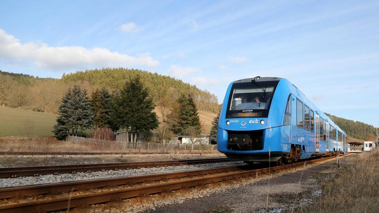 Ein blauer Zug mit Wasserstoffantrieb verlässt einen Bahnhof für eine Testfahrt.