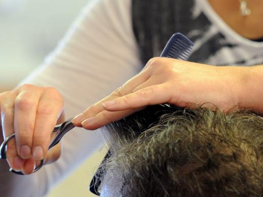 Eine Friseurin frisiert eine ältere Kundin.
