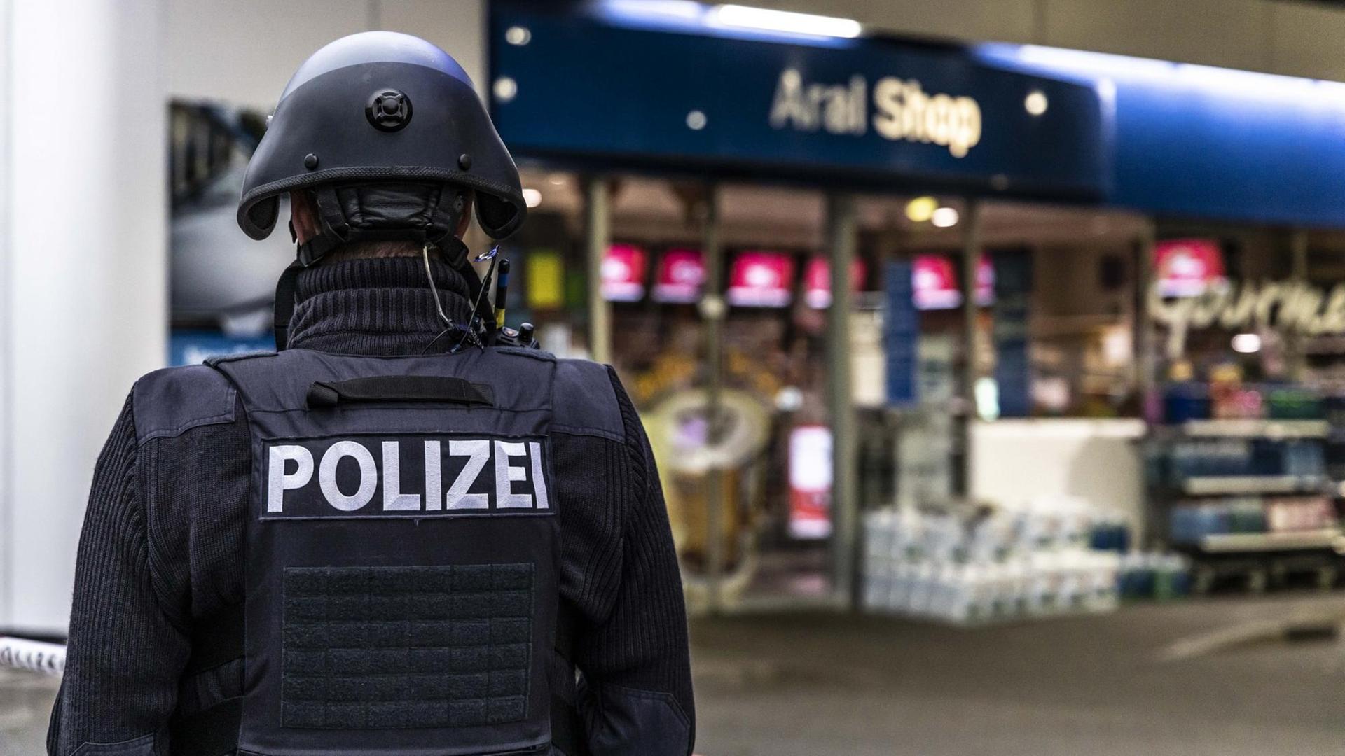 Ein Polizist sichert in den frühen Morgenstunden eine Tankstelle in Idar-Oberstein in Rheinland-Pfalz. Ein Polizist sichert in den frühen Morgenstunden eine Tankstelle in Idar-Oberstein in Rheinland-Pfalz.