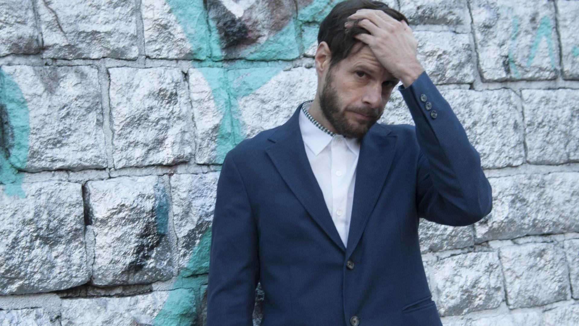 Der Feature-Autor Christian Lerch steht vor einer Wand und fasst sich in die Haare. Der Feature-Autor Christian Lerch steht vor einer Wand und fasst sich in die Haare.