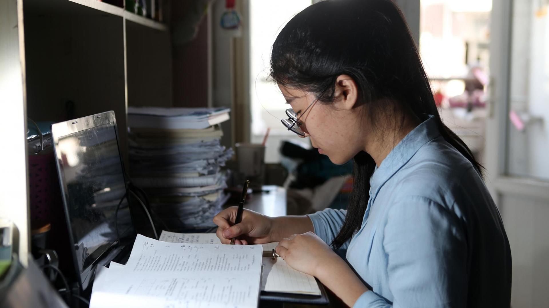 Die chinesische Studentin Tang Lisha sitzt am Schreibtisch und lernt im Studentenwohnheim der Chengdu Normal University
