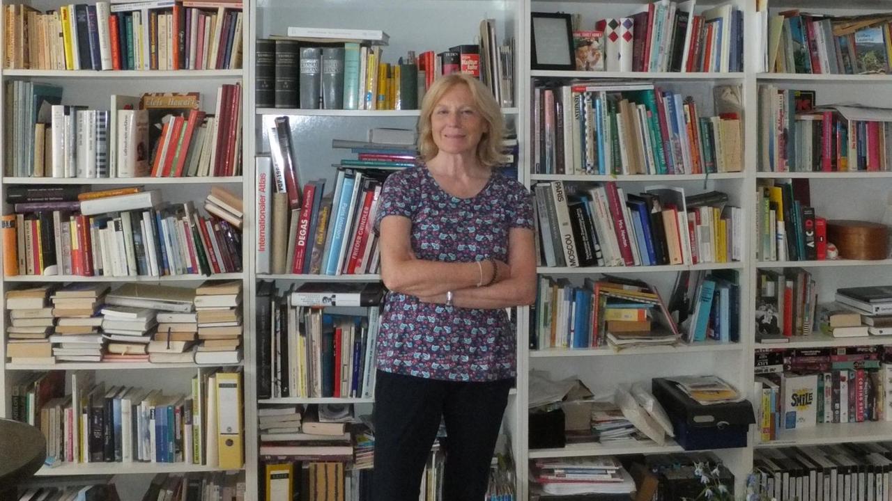 Maren Kroymann steht vor einem riesigen Bücherregal in ihrer Privatwohnung.