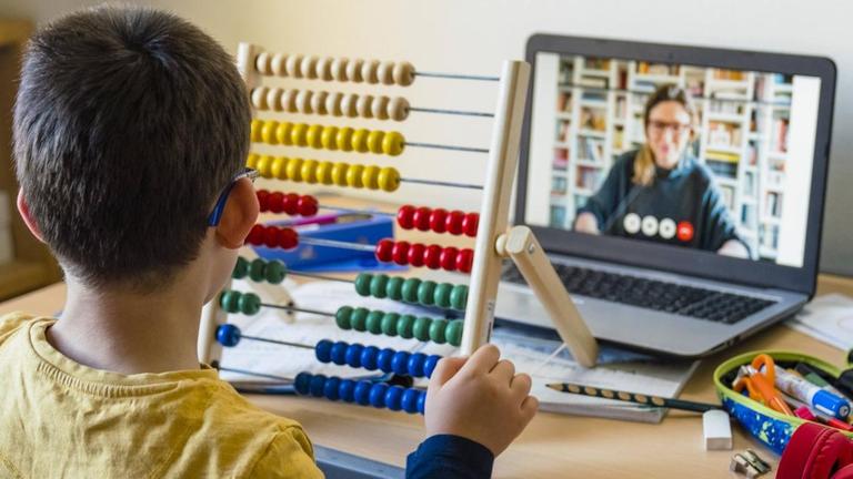 Schüler beim Unterricht zu Hause mit seiner per Video zugeschalteten Lehrerin Schüler beim Unterricht zu Hause mit seiner per Video zugeschalteten Lehrerin