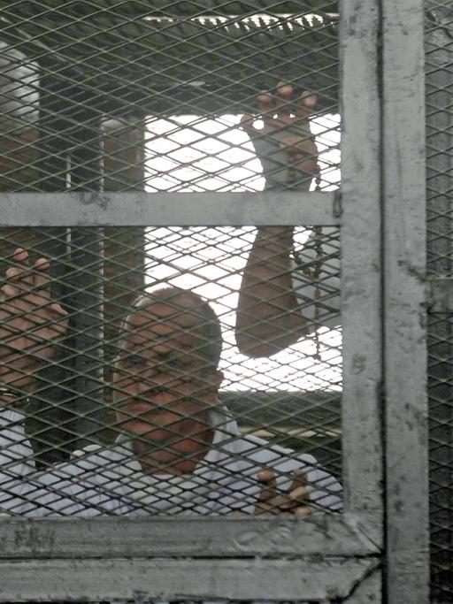 Die verurteilten Journalisten in einem Käfig vor Gericht