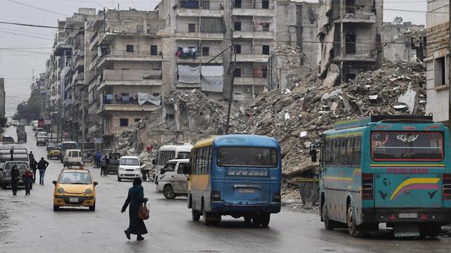 07.02.2019: Busse fahren auf einer Straße in Aleppo, zerstörte Häuser sind zu sehen