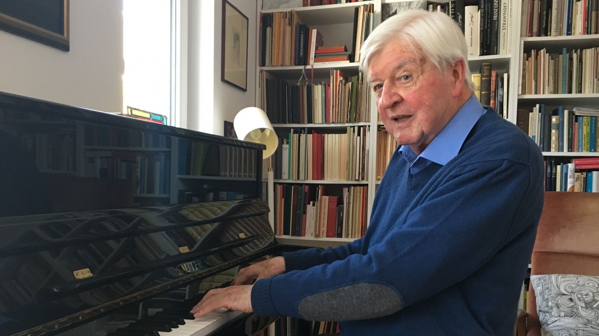 Hans Maier sitzt am Klavier, im Hintergrund eine Bücherwand. Hans Maier sitzt am Klavier, im Hintergrund eine Bücherwand.