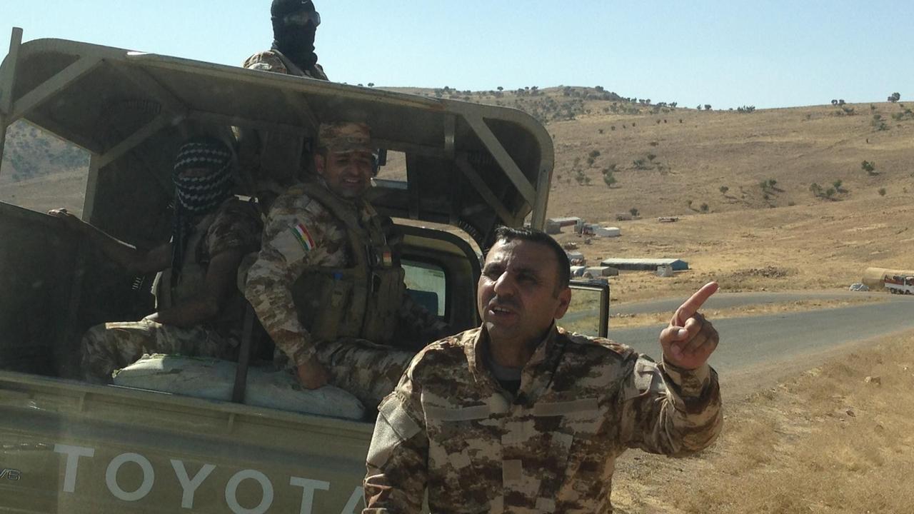 Ein jesidischer Kämpfer steht vor einem Pick Up im Sinjar-Gebirge