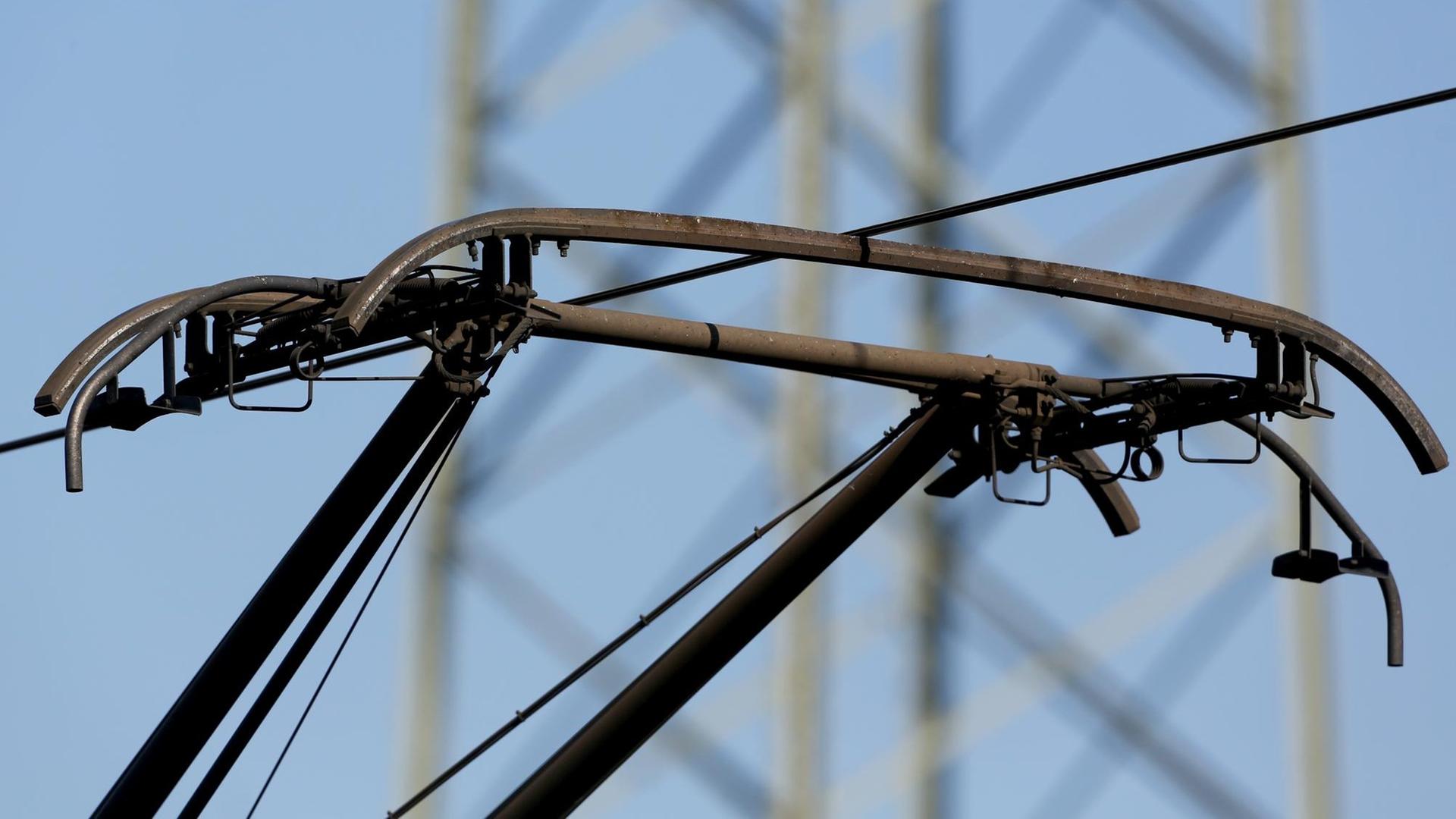 Das Bild zeigt den Stromabnehmer und das Kabel der Oberleitung, dahinter unscharf ein Strommast.