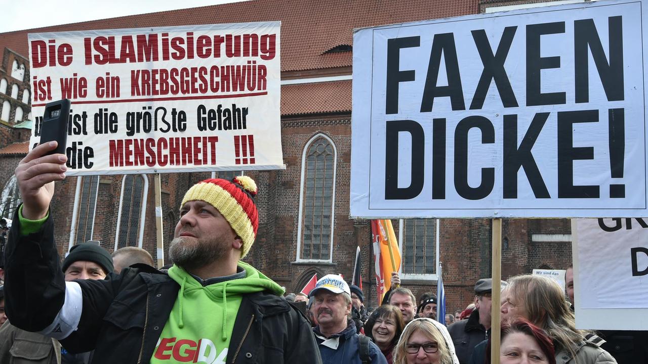 Cottbus: Ein Demonstrant filmt mit dem Handy die Plakate auf dem Oberkirchplatz. Der Verein Zukunft Heimat e.V. hatte zu der Demonstration aufgerufen. Cottbus: Ein Demonstrant filmt mit dem Handy die Plakate auf dem Oberkirchplatz. Der Verein Zukunft Heimat e.V. hatte zu der Demonstration aufgerufen.