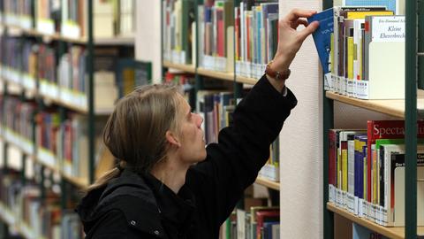 In der Stadtbibliothek Rostock in der Kröpeliner Straße greift ein Mann nach einem Buch.