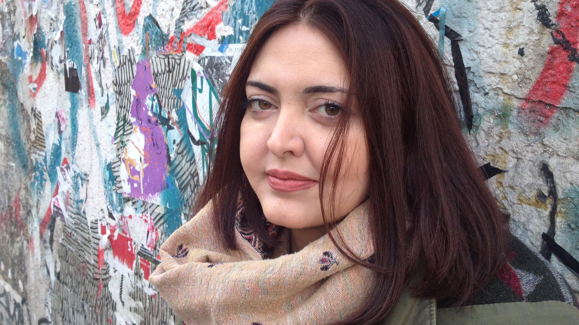 Porträtfoto der syrischen Schriftstellerin Rasha Abbas vor einer Wand mit Graffiti. Sie lebt momentan in Berlin im Exil.