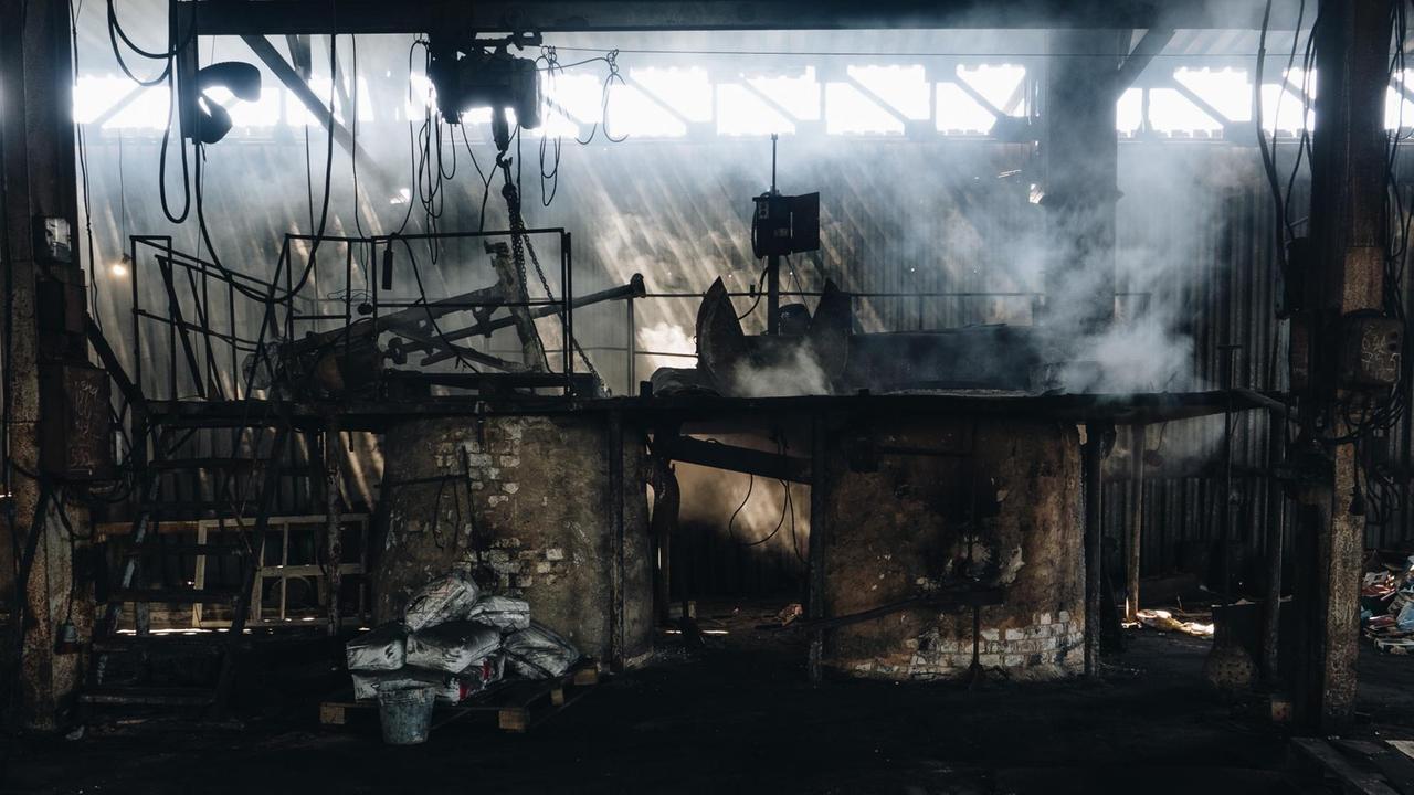 Totale der Metallfabrik. Durch die Fenster ganz oben scheint Sonnenlicht auf den aufsteigenden Rauch. Totale der Metallfabrik. Durch die Fenster ganz oben scheint Sonnenlicht auf den aufsteigenden Rauch.
