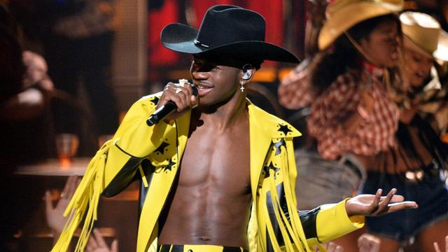Rapper Lil Nas X singt mit schwarzem Cowboyhut und gelber Fransenjacke