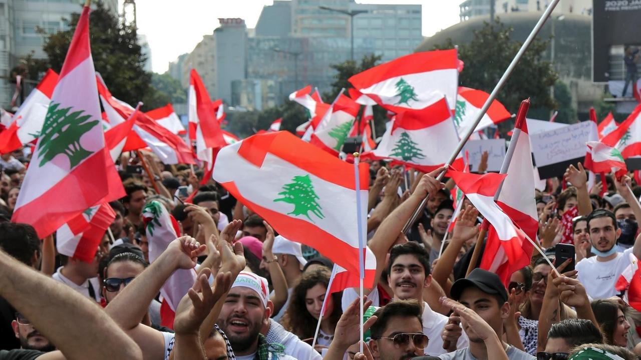 Demonstranten in Beirut schwenken libanesische Flaggen während eines Protests. Demonstranten in Beirut schwenken libanesische Flaggen während eines Protests.