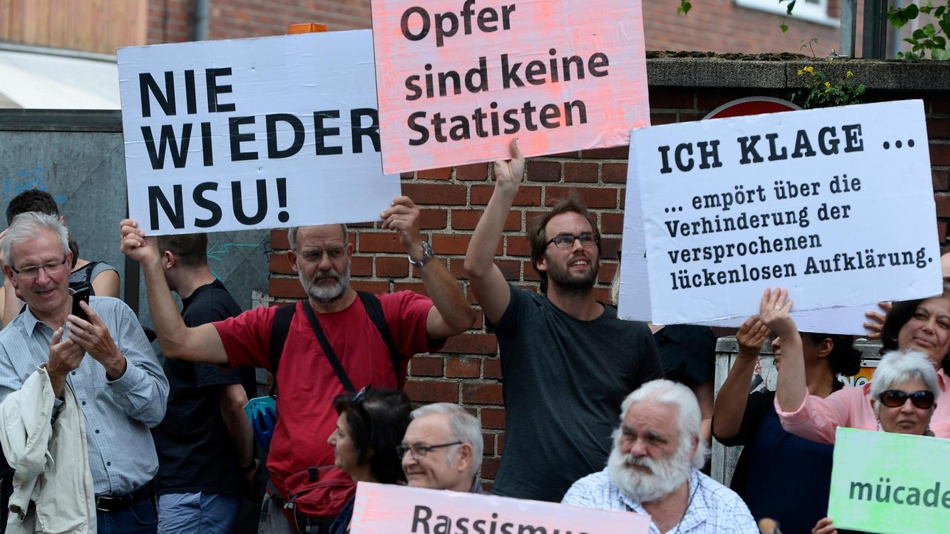 Teilnehmer einer Schweigeminute erinnern 2019 mit Plakaten auf der Kölner Keupstrasse am 15. Jahrestag an den NSU-Nagelbombenanschlag, bei dem dort 22 Menschen verletzt wurden, vier davon schwer. Am 9. Juni 2004 hatten