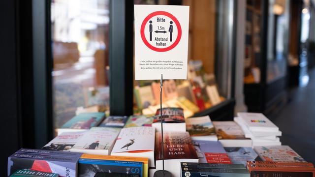 Ein Schild mit einem Hinweis auf die Abstandsregeln steht vor einer Buchhandlung in Hamburg.