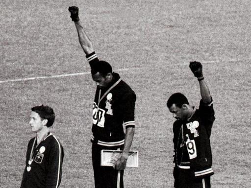 Tommie Smith (Mitte) und John Carlos (rechts) bei der Siegerehrung der 200-Meterläufer 1968 in Mexiko-City: Der Gold- und der Silbermedaillengewinner heben die Faust als "Black Power"-Geste für die Bürgerrechte der Schwarzen.