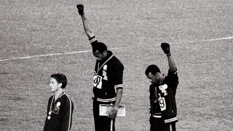 Tommie Smith (Mitte) and John Carlos (rechts) bei der Siegerehrung der 200-Meterläufer 1968 in Mexiko-City: Der Gold- und der Silbermedaillengwinner heben die Faust als "Black Power"-Geste für die Bürgerrechte der Schwarzen.