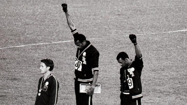 Tommie Smith (Mitte) and John Carlos (rechts) bei der Siegerehrung der 200-Meterläufer 1968 in Mexiko-City: Der Gold- und der Silbermedaillengwinner heben die Faust als "Black Power"-Geste für die Bürgerrechte der Schwarzen. Tommie Smith (Mitte) and John Carlos (rechts) bei der Siegerehrung der 200-Meterläufer 1968 in Mexiko-City: Der Gold- und der Silbermedaillengwinner heben die Faust als "Black Power"-Geste für die Bürgerrechte der Schwarzen.