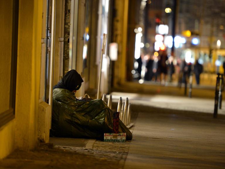 Ein Obdachloser sitzt im Februar 2014 in Berlin Mitte auf dem Gehweg.