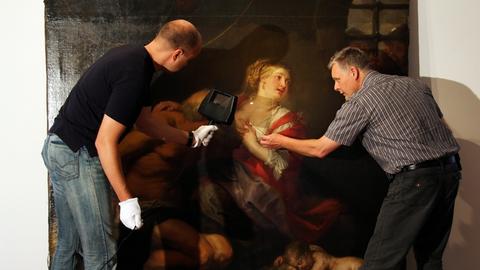 Zwei Restauratoren vor dem Gemälde "Caritas Romana" von Peter Paul Rubens.