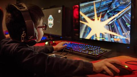 Ein kleiner Junge spielt Fortnite am Computer.
