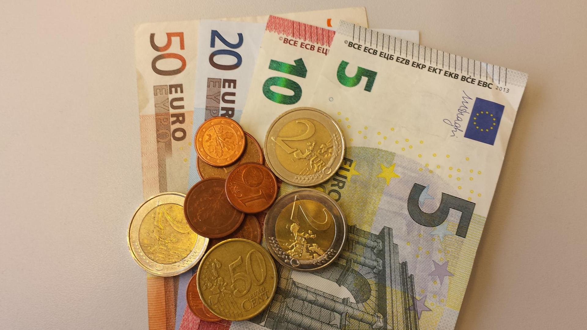 Euro-Geldscheine liegen mit Euro-Münzen auf einem Stapel. Euro-Geldscheine liegen mit Euro-Münzen auf einem Stapel.