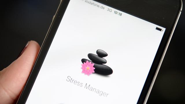 Auf einem Display eines Mobiltelefons ist eine App zur Messung des Stresspegels abgebildet.