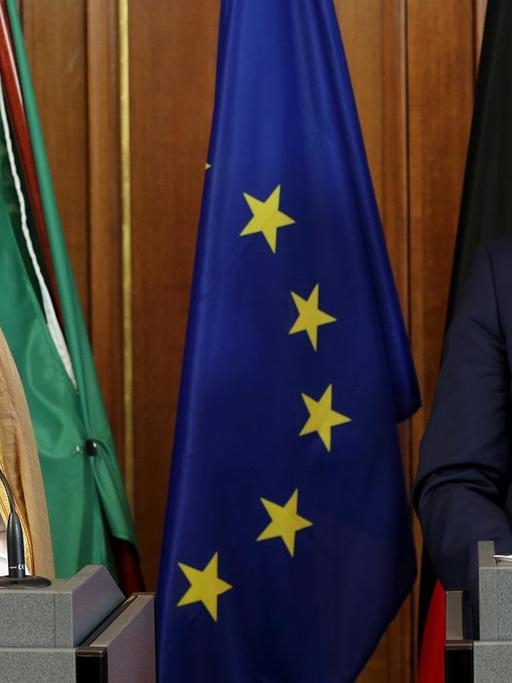 Steinmeier und Jubair stehen nebeneinander an Podesten und lachen. Hinter ihnen die Flaggen beider Länder und die Europa-Flagge.