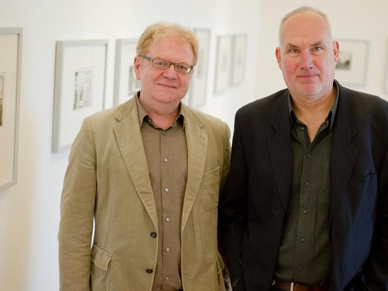 Die Karikaturisten Achim Greser und Heribert Lenz stehen vor ihren Bildern