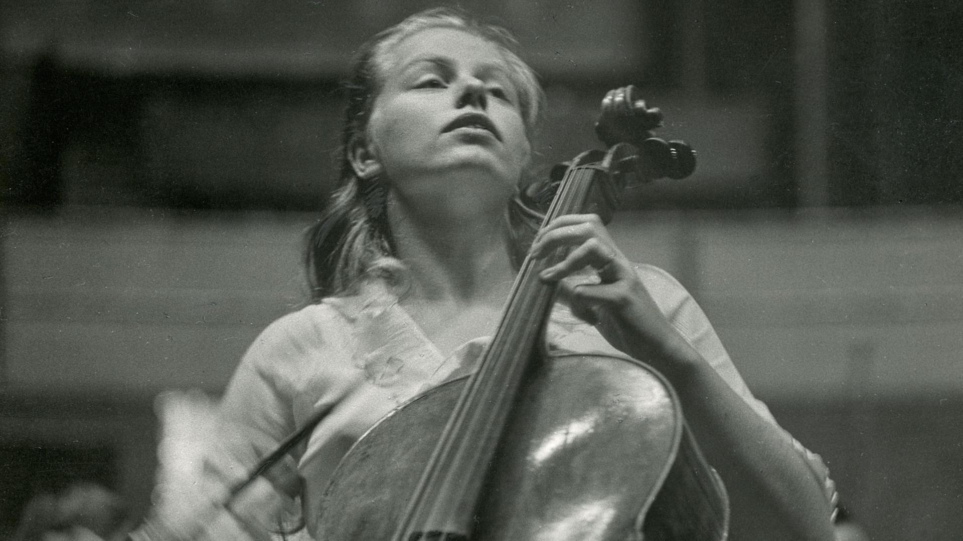 Eine Frau mit Cello sitzt auf einer Bühne und spielt Musik
