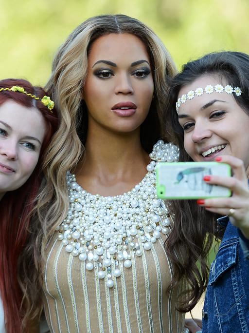 Zwei Mitarbeiterinnen von Madame Tussauds machen am 20.8.2014 bei einem Fototermin im Londoner Regent's Park ein Selfie mit der Wachsfigur der US-Sängerin Beyoncé.