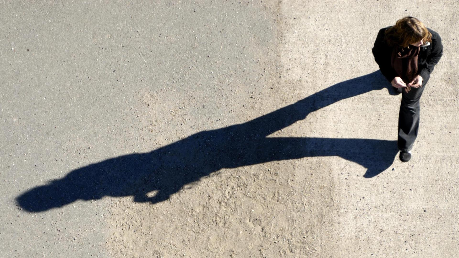 Der langgezogene Schatten einer Spaziergängerin.