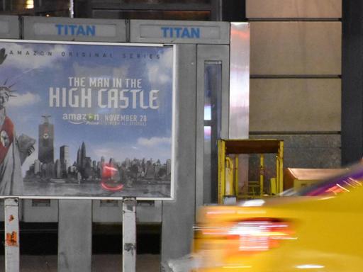 Eine Taxi fährt in New York an der Werbung für die TV-Serie "The Man in the High Castle" vorbei. Das Plakat zeigt die New Yorker Freiheitsstatue mit Hitlergruß und roter Nazischärpe.