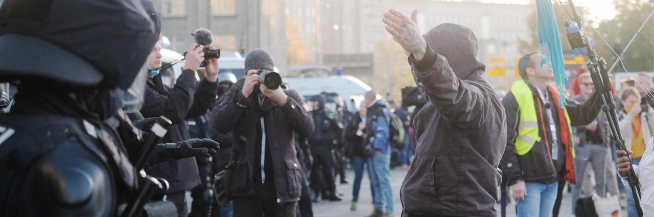 07.11.2020, Sachsen, Leipzig: Teilnehmer der Demonstration der Initiative ?Querdenken? rufen und gestikulieren mit ausgebreiteten Armen auf dem Augustusplatz vor Medienvertretern und Polizisten. An der Kundgebung gegen die von Bund und Ländern beschlossenen Corona-Maßnahmen nehmen mehrere Tausend Menschen teil. Foto: Sebastian Willnow/dpa-Zentralbild/dpa | Verwendung weltweit 07.11.2020, Sachsen, Leipzig: Teilnehmer der Demonstration der Initiative ?Querdenken? rufen und gestikulieren mit ausgebreiteten Armen auf dem Augustusplatz vor Medienvertretern und Polizisten. An der Kundgebung gegen die von Bund und Ländern beschlossenen Corona-Maßnahmen nehmen mehrere Tausend Menschen teil. Foto: Sebastian Willnow/dpa-Zentralbild/dpa | Verwendung weltweit