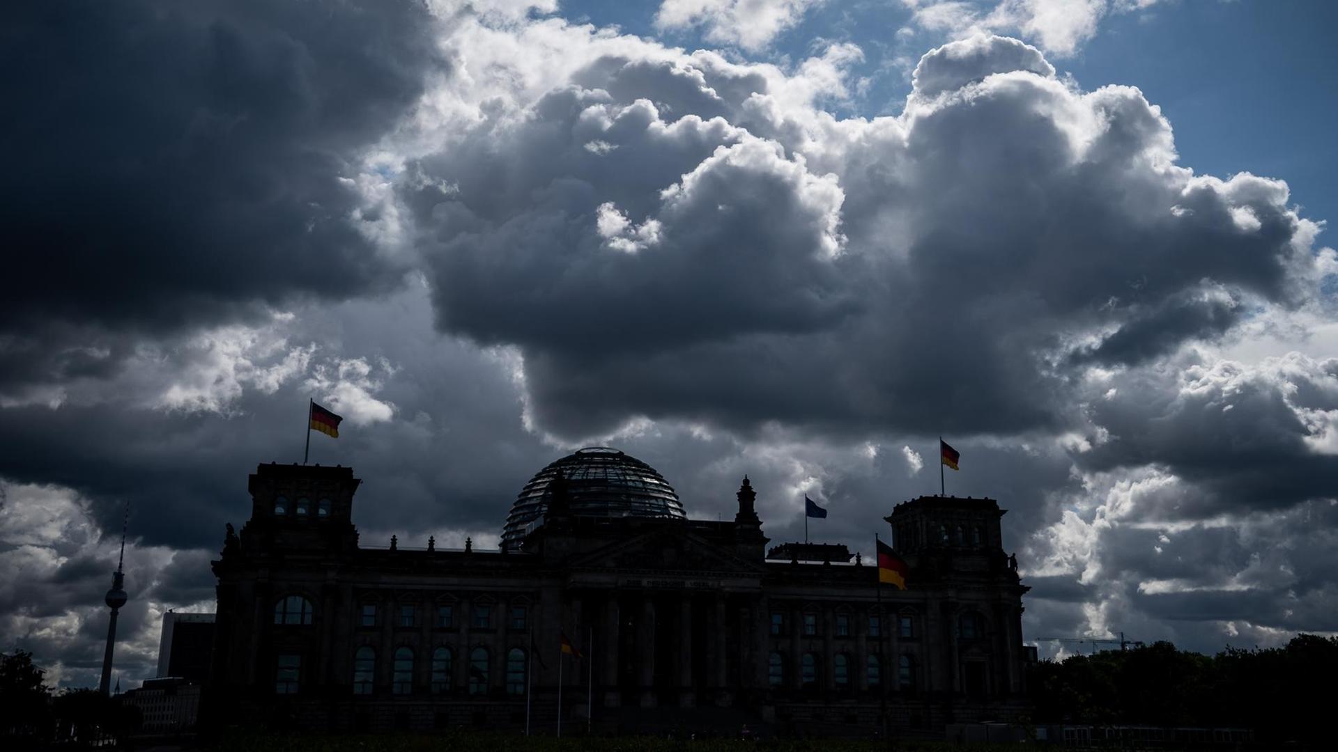 Die Sonne versteckt sich hinter dunklen Wolken über dem Reichstag, dem Sitz des Deutschen Bundestags. Die Sonne versteckt sich hinter dunklen Wolken über dem Reichstag, dem Sitz des Deutschen Bundestags.