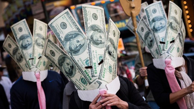 Demonstranten bei den "Occupy Wall Street"-Protesten, verkleidet mit Anzug, Kragen und Krawatte und überdimensionierten Geldscheinen vor dem Gesicht