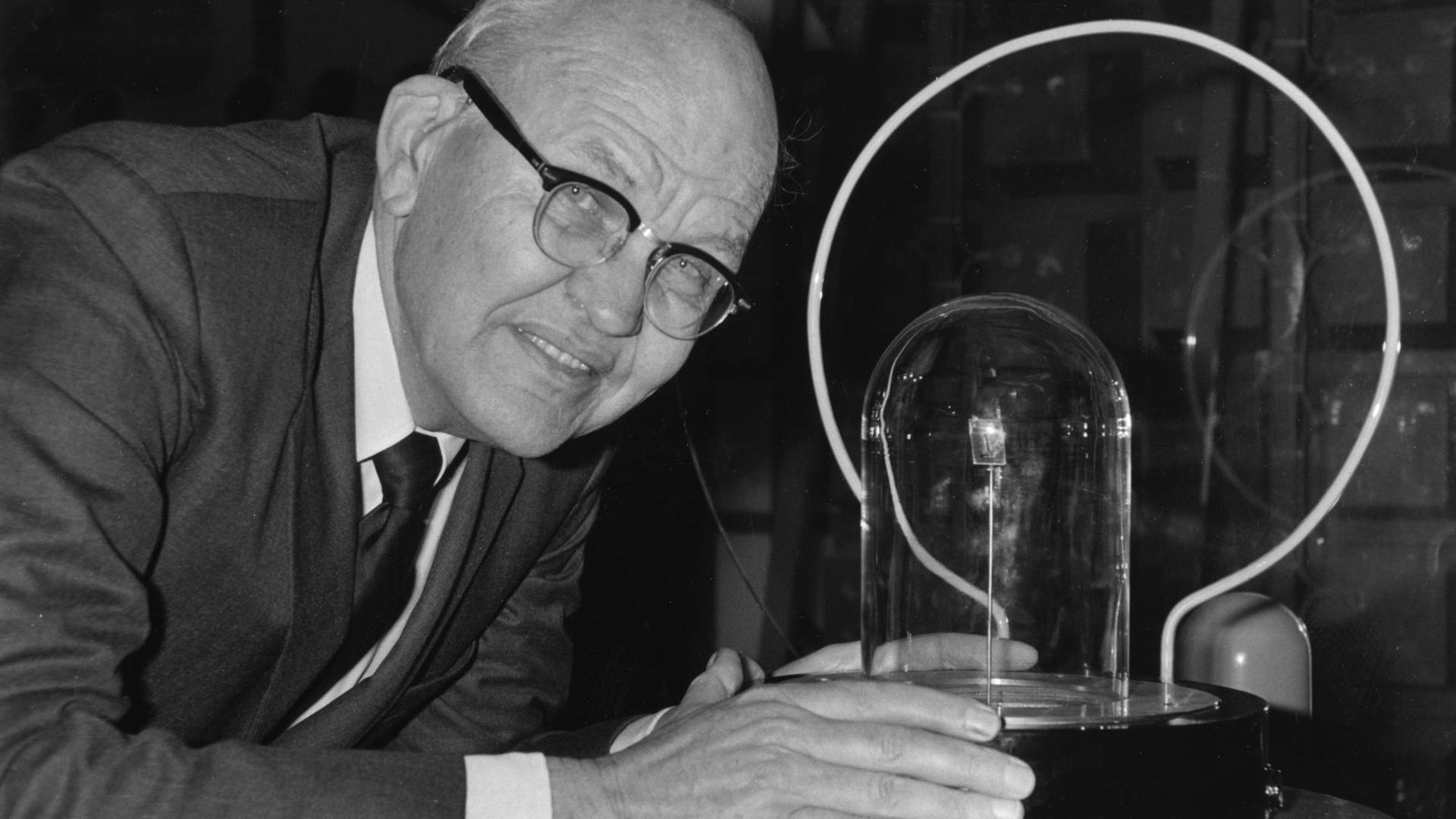 Jack Kilby mit seiner Erfindung von 1958, dem ersten integrierten Schaltkreis der Welt, auf einer Ausstellung 1985 in Tsukuba in der Nähe von Tokio. Jack Kilby mit seiner Erfindung von 1958, dem ersten integrierten Schaltkreis der Welt, auf einer Ausstellung 1985 in Tsukuba in der Nähe von Tokio.
