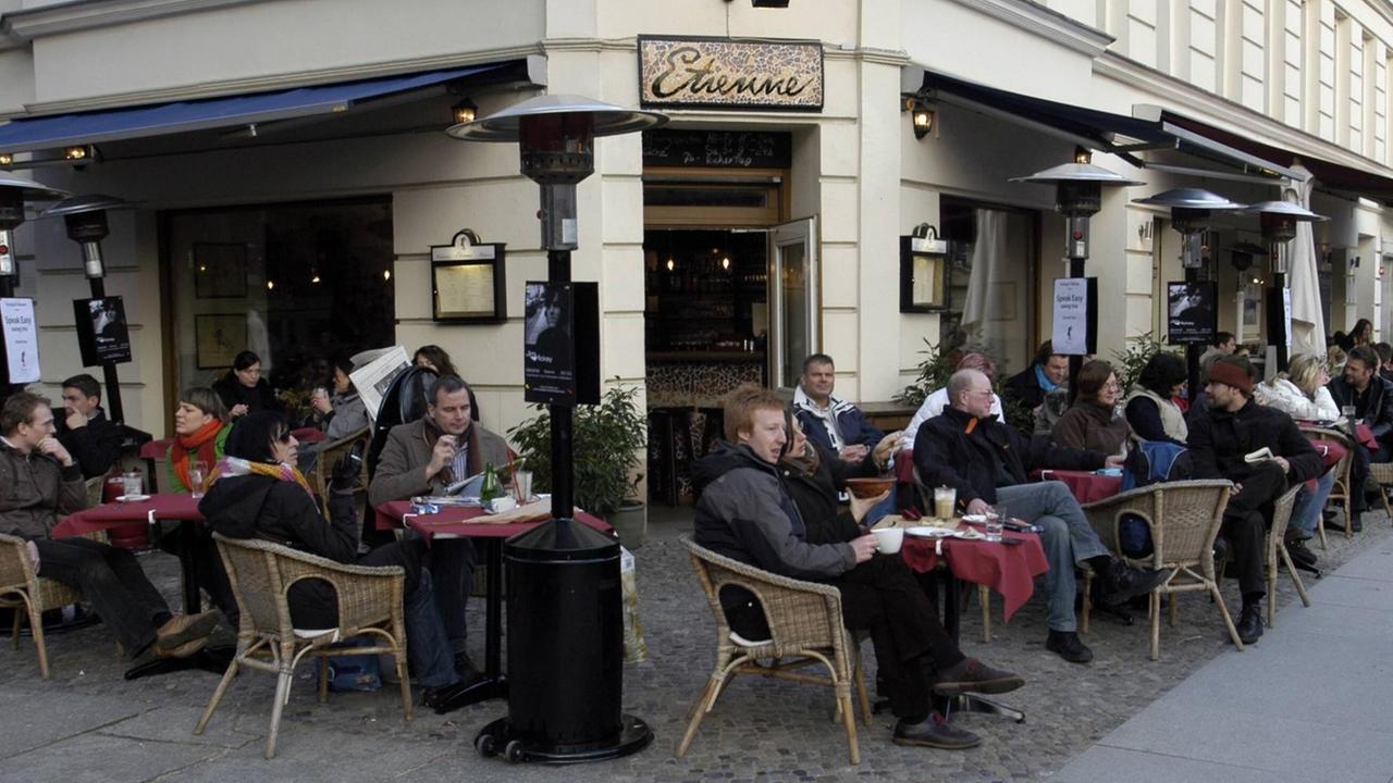 Gäste vor dem Restaurant - Etienne - am Kollwitzplatz in Berlin-Prenzlauer Berg. Sie sitzen an Tischen draußen vor dem Restaurant.