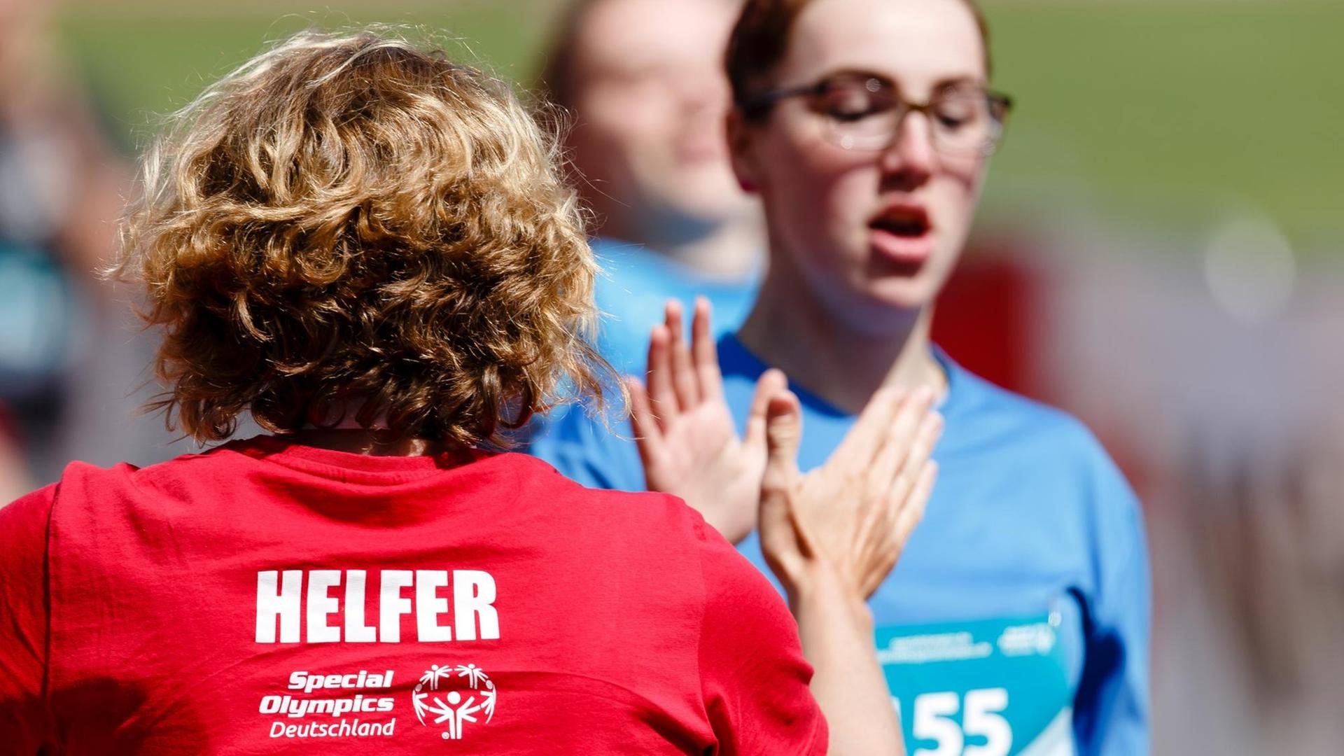 Eine Helferin (l) klatscht bei den Special Olympics, den nationalen Sommerspiele für Menschen mit geistiger oder mehrfacher Behinderung, mit der Athletin Vanessa Petry von der Friedrich-Joachim-Stengel-Schule in Heusweiler ab.