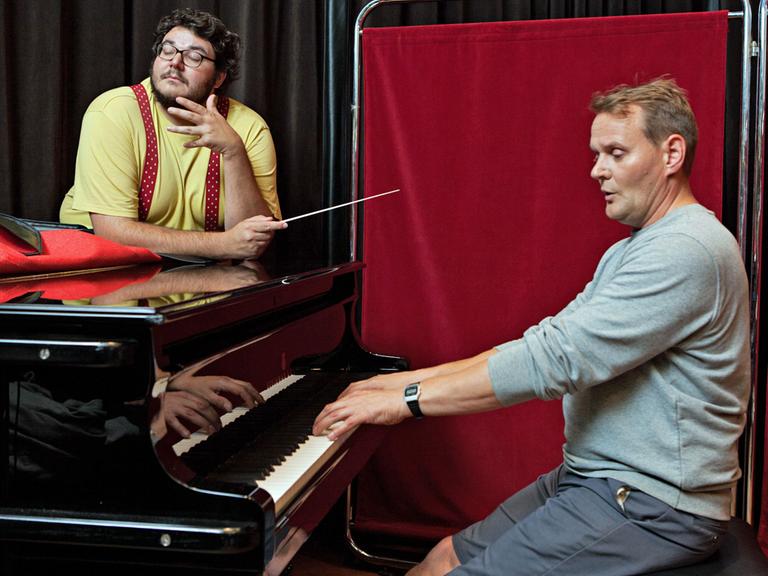 Axel Ranisch und Devid Striesow: Axel schwingt den Taktstock, während Devid Klavier spielt.