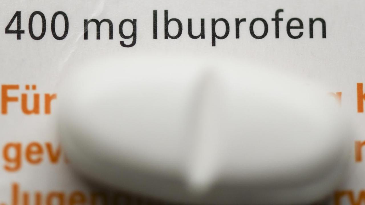 Eine Tablette mit dem Wirkstoff Ibuprofen liegt auf einer Medikamentenschachtel. Eine Tablette mit dem Wirkstoff Ibuprofen liegt auf einer Medikamentenschachtel.